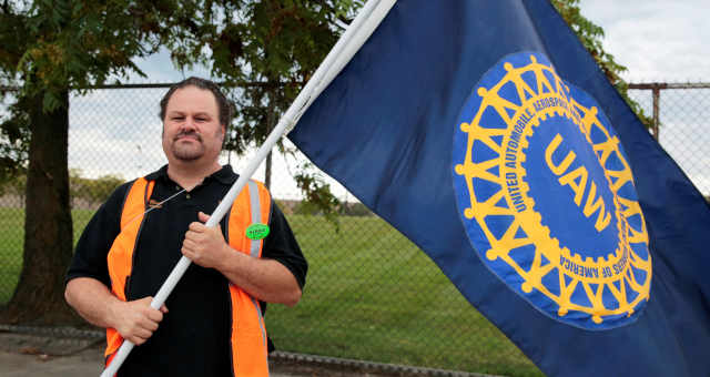 Funcionário da indústria automobilística com bandeira do sindicato United Auto Worker, em Detroit