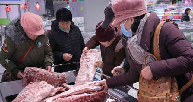 Consumidores selecionam carne de porco congelada em Nantong, China