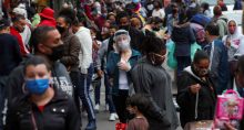 Mulher usando máscara protetora e protetor facial fala ao telefone enquanto pessoas caminham em uma popular rua comercial em meio ao surto de Covid-19 em São Paulo, Brasil, 15 de julho de 2020. REUTERS/Amanda Perobelli