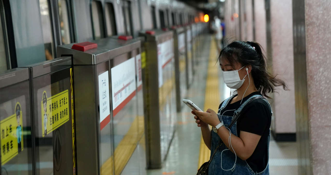 Mulher usa smartphone em metrô de Pequim