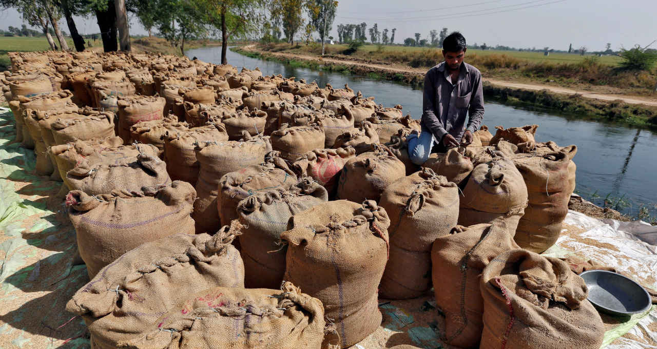 Trabalhador embala um saco cheio de arroz nos arredores de Ahmedabad